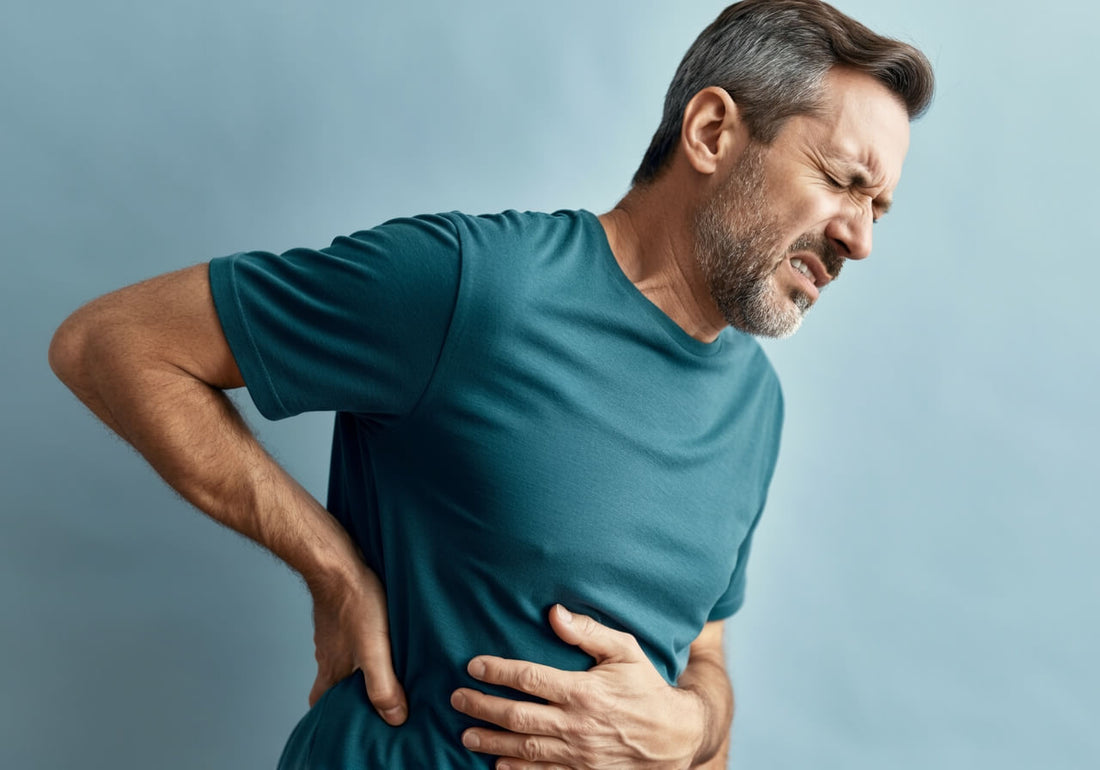 A middle-aged man wearing a teal shirt clutching his upper abdomen in pain. Liver pain location.