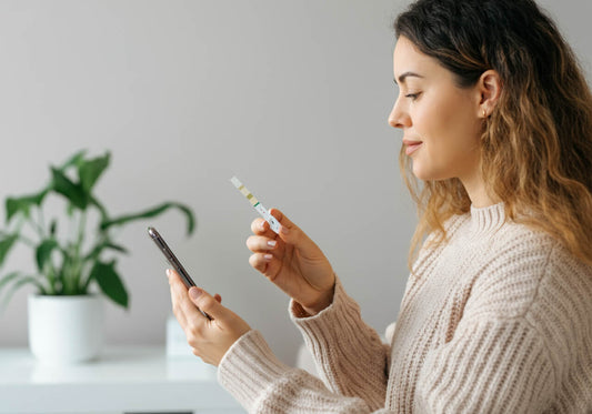 Woman looking at her phone to interpret her urine dipstick result